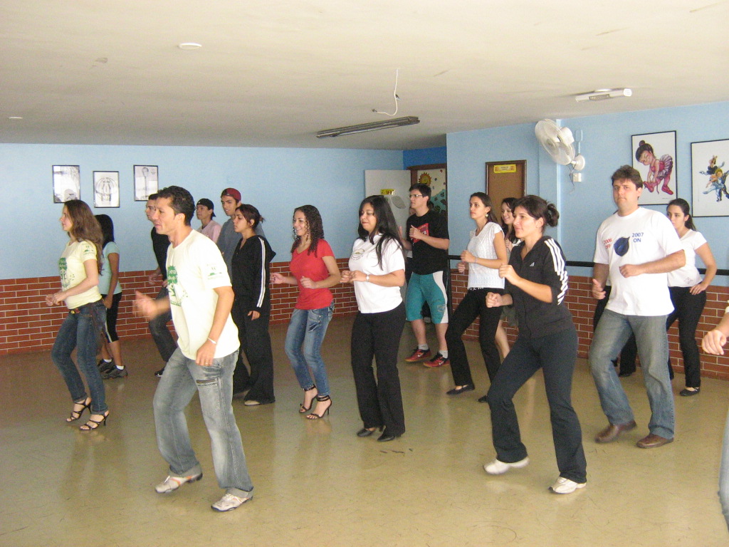 Participantes acompanham demonstração de dança diante dos espelhos do salão