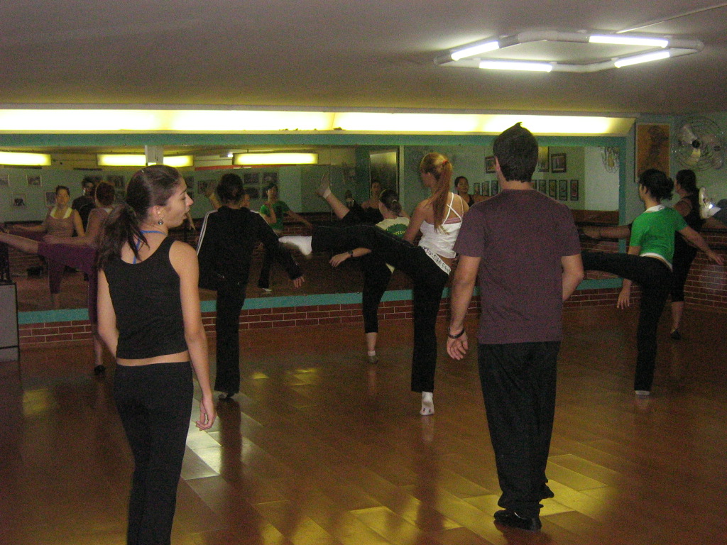 Grupo pratica sequência de dança conduzida no centro do salão