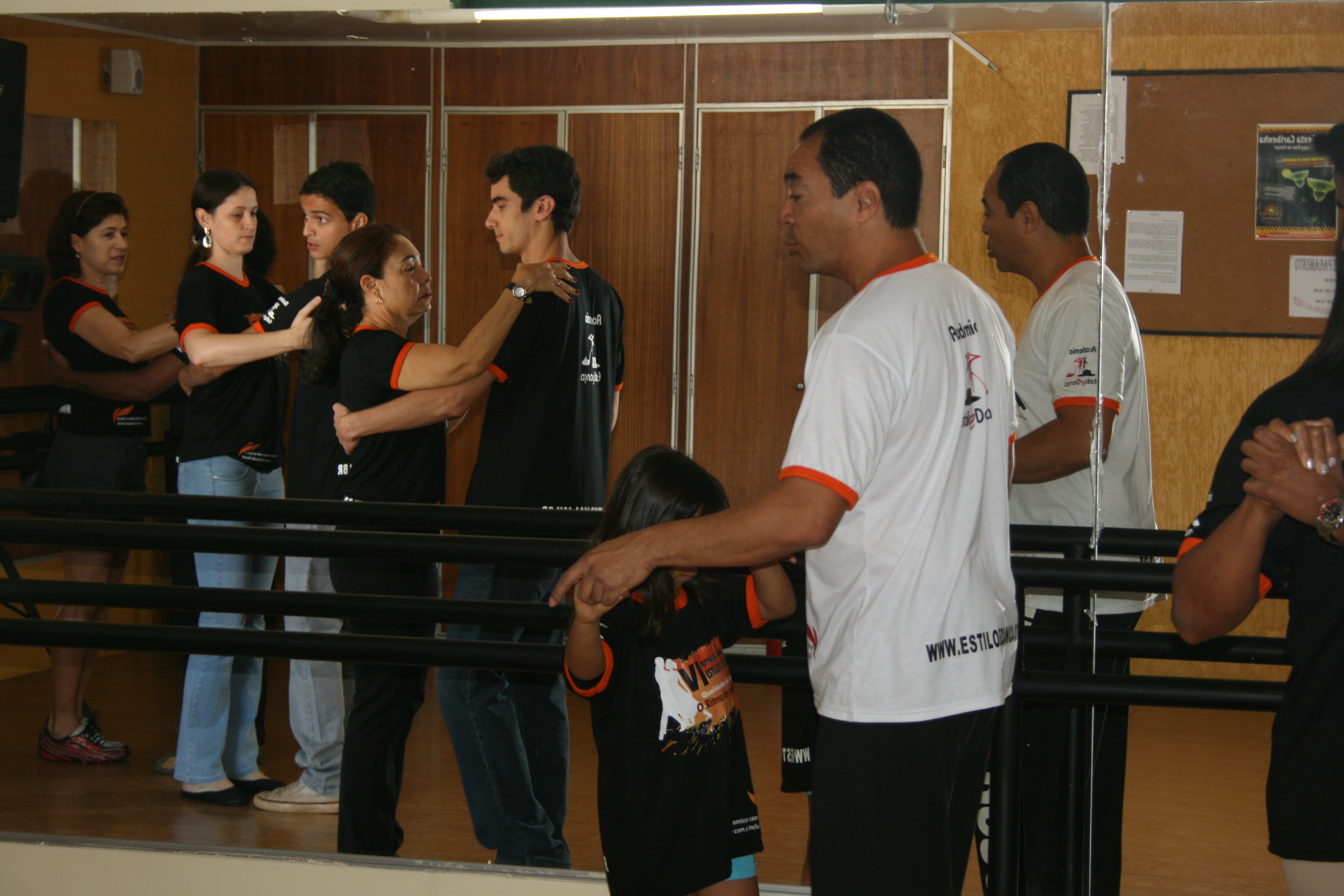 Participantes praticam dança em pares diante dos espelhos
