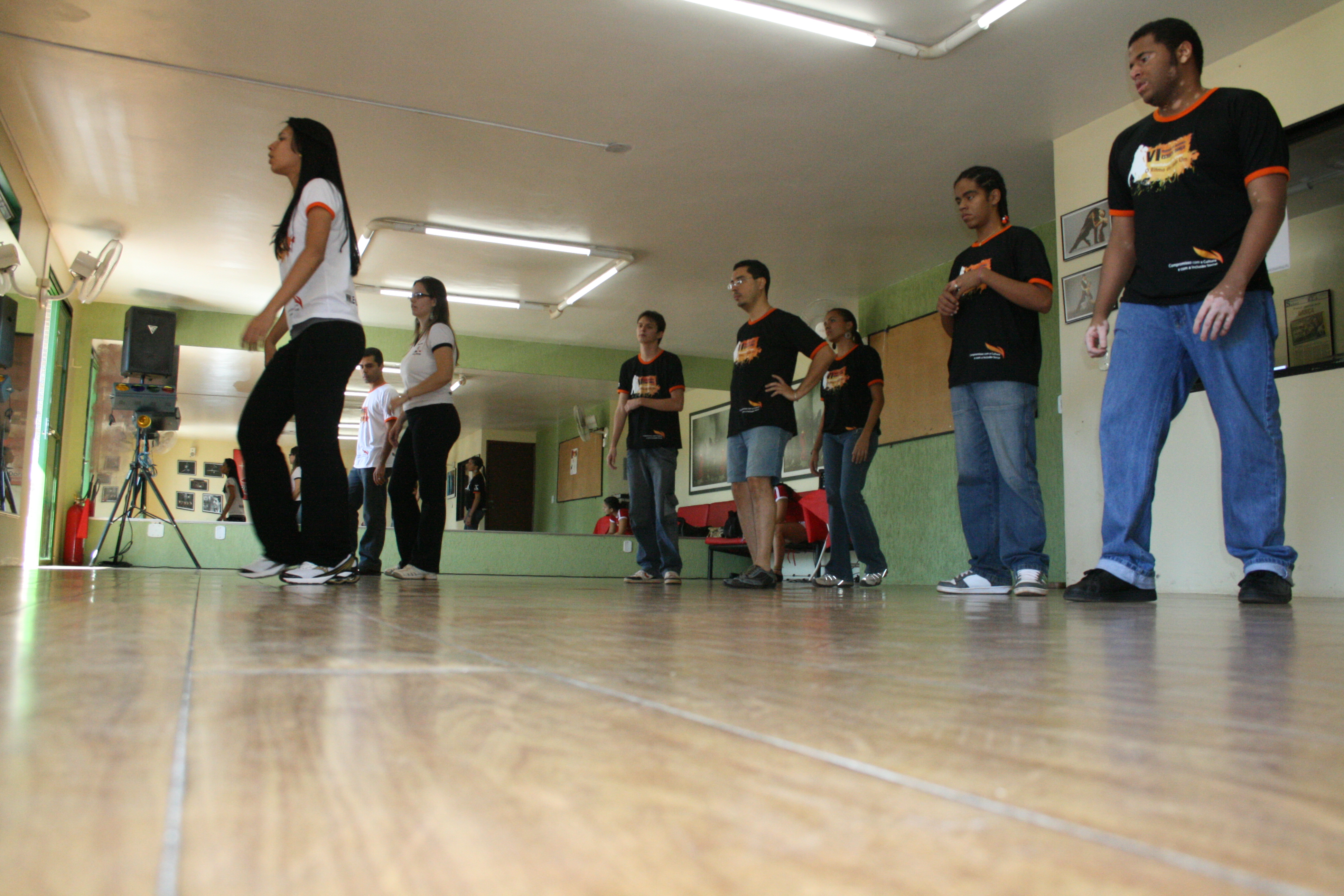 Participantes executam sequência de dança em linha diante dos espelhos
