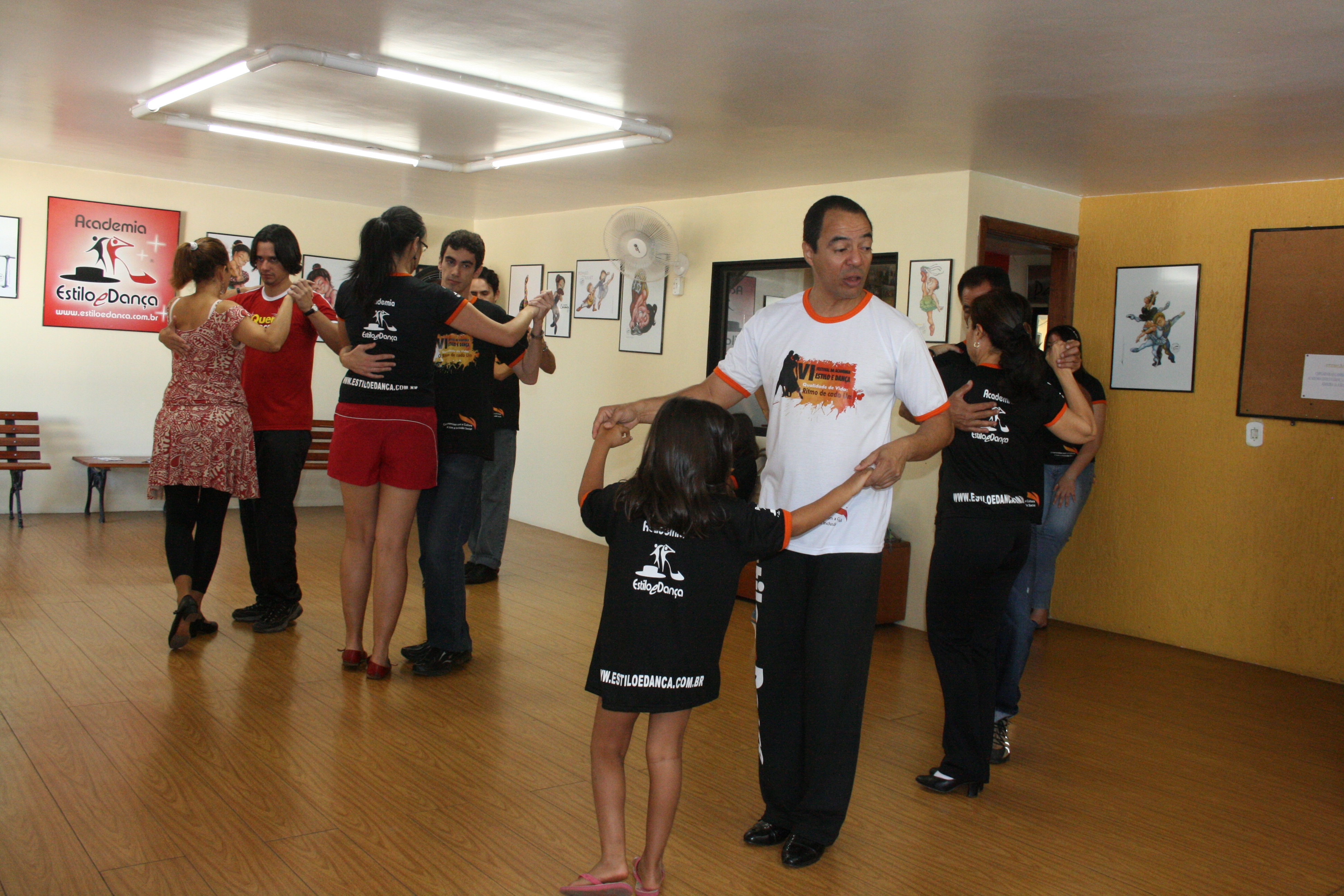 Integrante conduz demonstração de dança com participante diante do grupo
