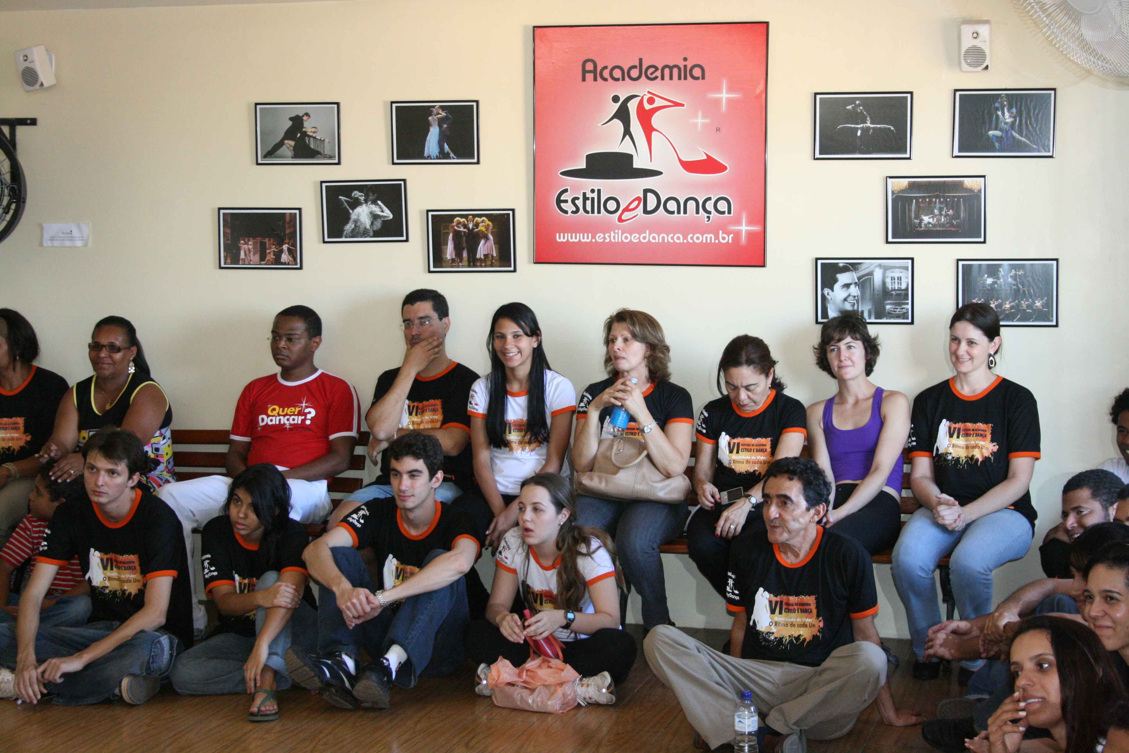 Grupo de participantes sentado diante da identidade visual da Academia