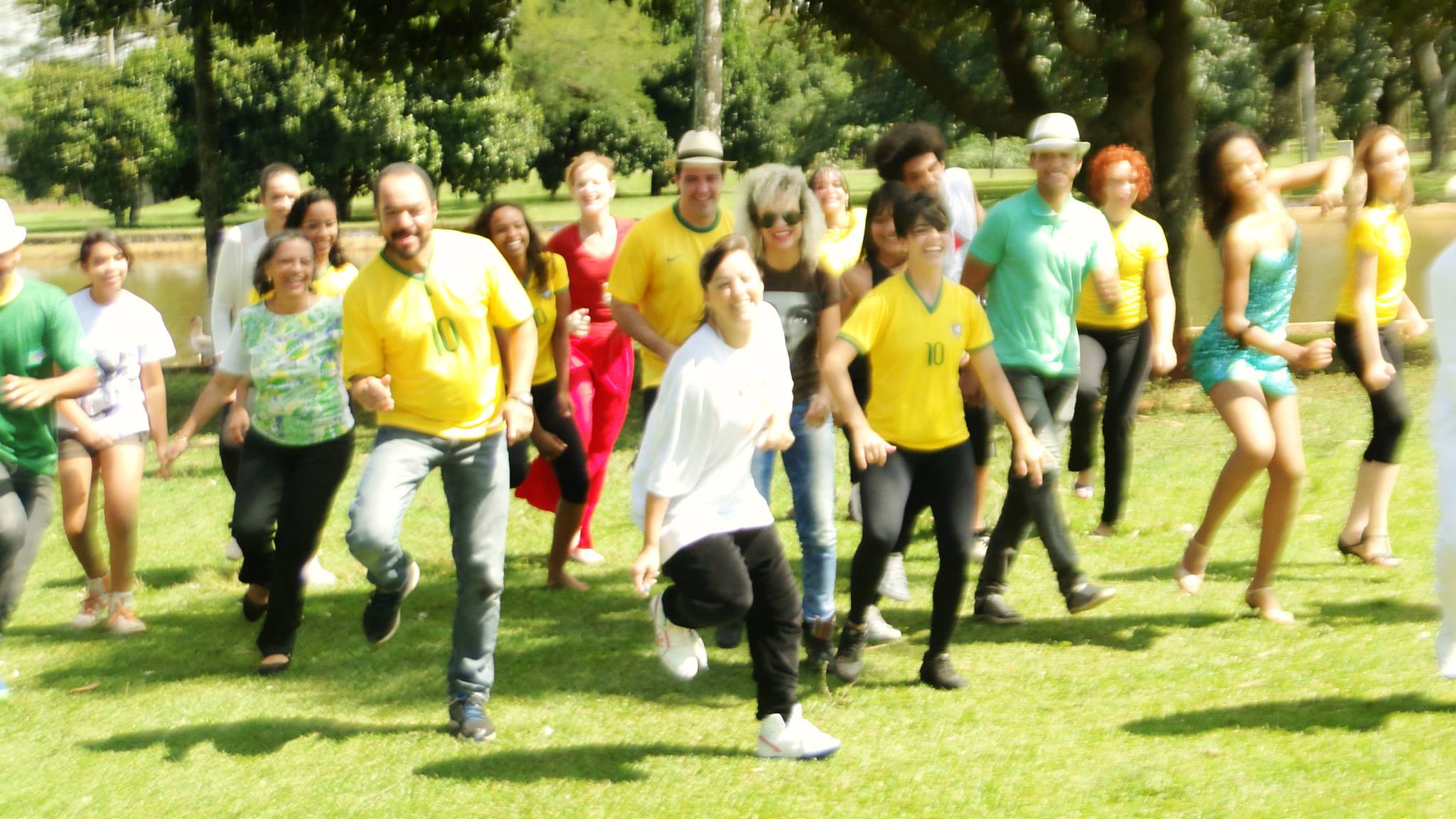 Grupo numeroso avança em movimento coletivo sobre o gramado de uma área arborizada.
