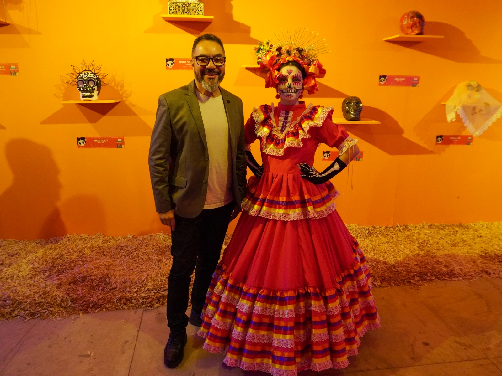 João Carlos Corrêa posa ao lado da Catrina mexicana Claudia Yerena, com maquiagem de caveira, traje vermelho e adorno floral