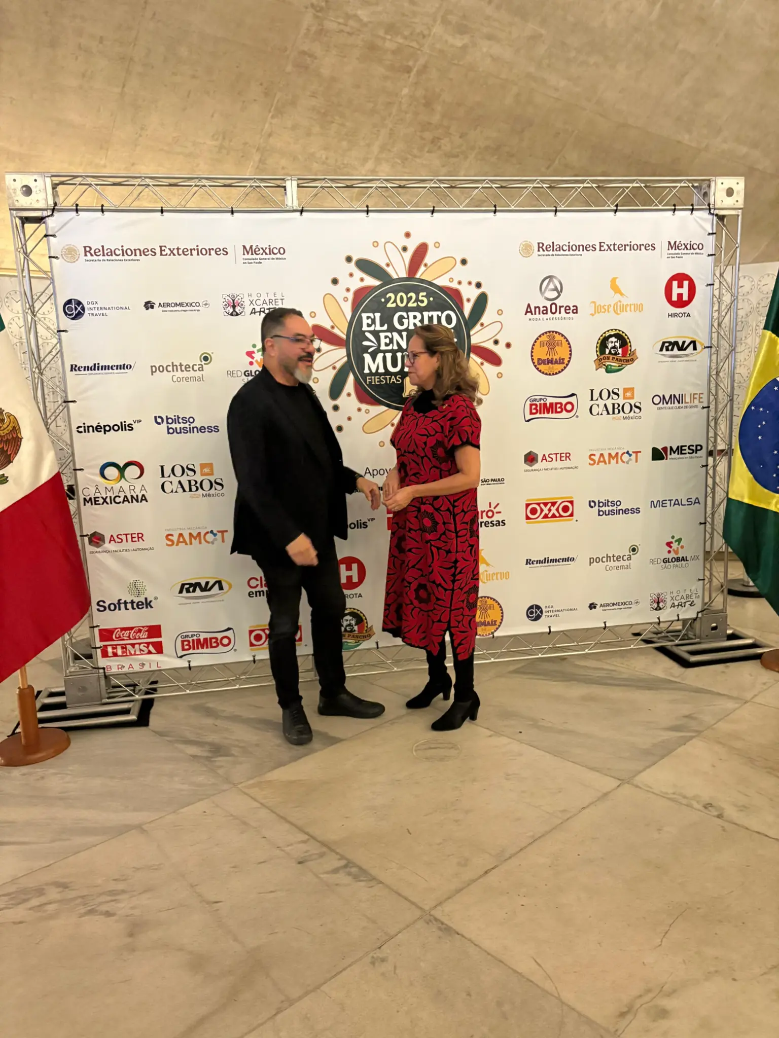 João Carlos Corrêa conversa com Claudia Velasco Osorio diante do painel e das bandeiras do México e do Brasil
