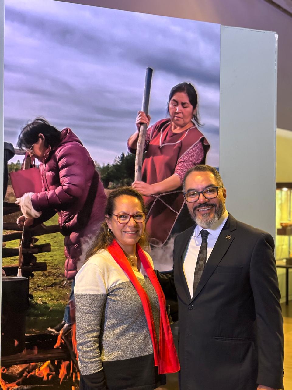 João Carlos Corrêa e Claudia Velasco Osorio posam diante de painel fotográfico em exposição do Consulado do Chile no Memorial