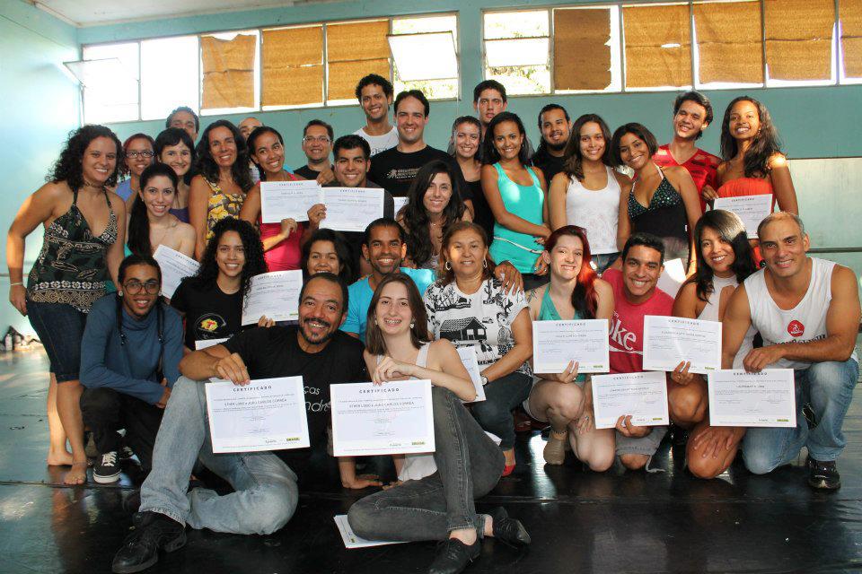 Grande grupo posa no salão, com vários participantes exibindo certificados para a câmera.