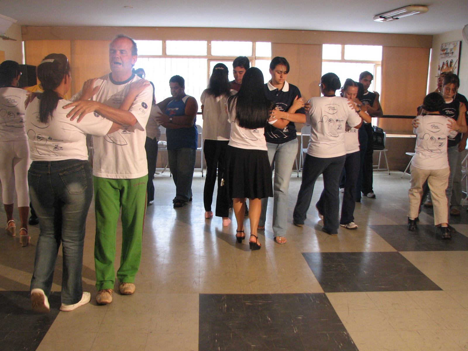 Várias duplas praticam dança de salão simultaneamente durante a aula