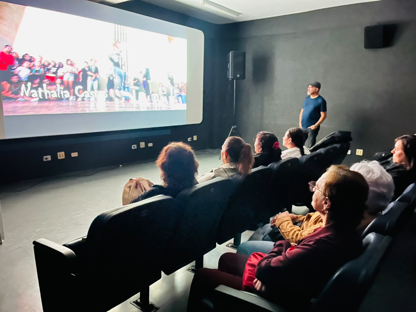 João Carlos Corrêa acompanha uma apresentação em vídeo diante do público na Fábrica de Cultura de Santos