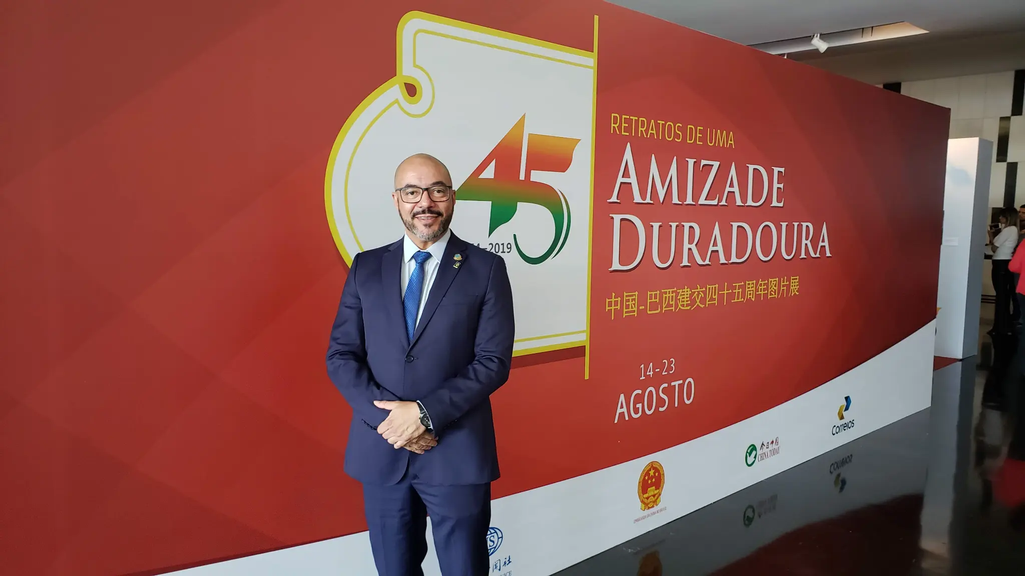 João Carlos Corrêa diante de painel comemorativo sobre relações entre Brasil e China.