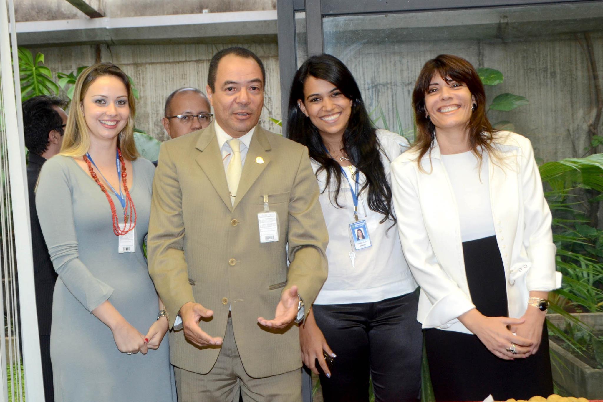 João Carlos Corrêa e três mulheres posam juntos em espaço interno com plantas ao fundo.