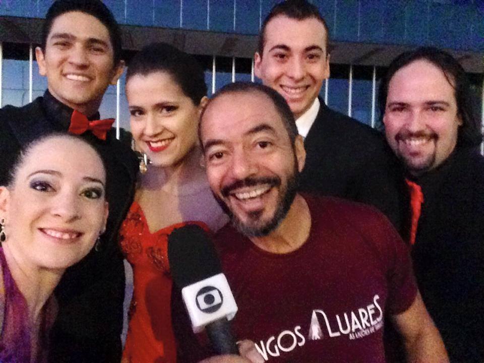 João Carlos Corrêa e integrantes de Tangos e Luares reunidos alrededor del micrófono de una emisora durante la cobertura televisiva