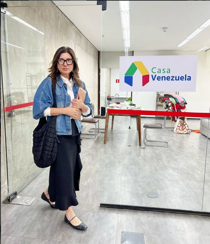 Blanca Montilla está de pie frente a una división de vidrio, con el logotipo de Casa Venezuela visible en la sala del fondo