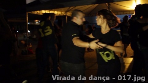 Casal dança sob a estrutura coberta da Virada da Dança durante a noite.