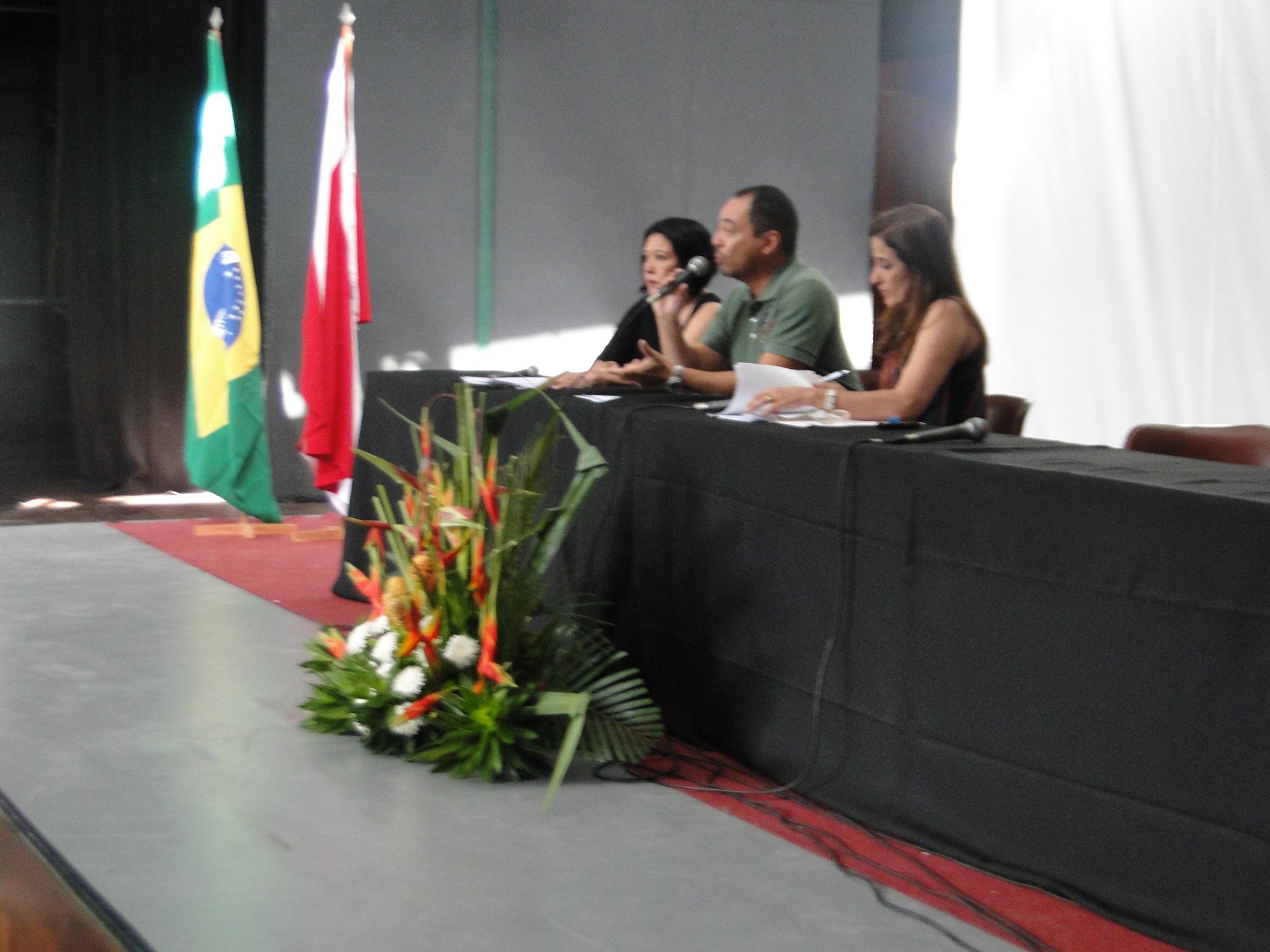 João Carlos Corrêa fala ao microfone em mesa de trabalho, diante das bandeiras do Brasil e do Pará.