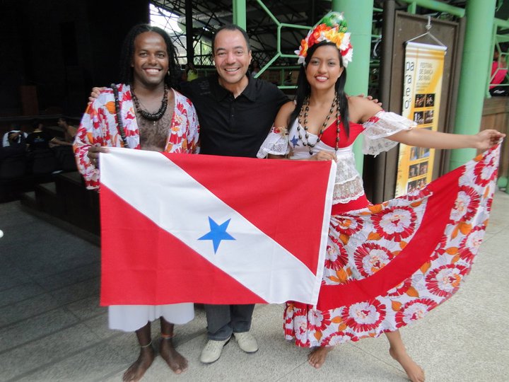 Três participantes posam com a bandeira do Pará e trajes de expressão cultural regional.