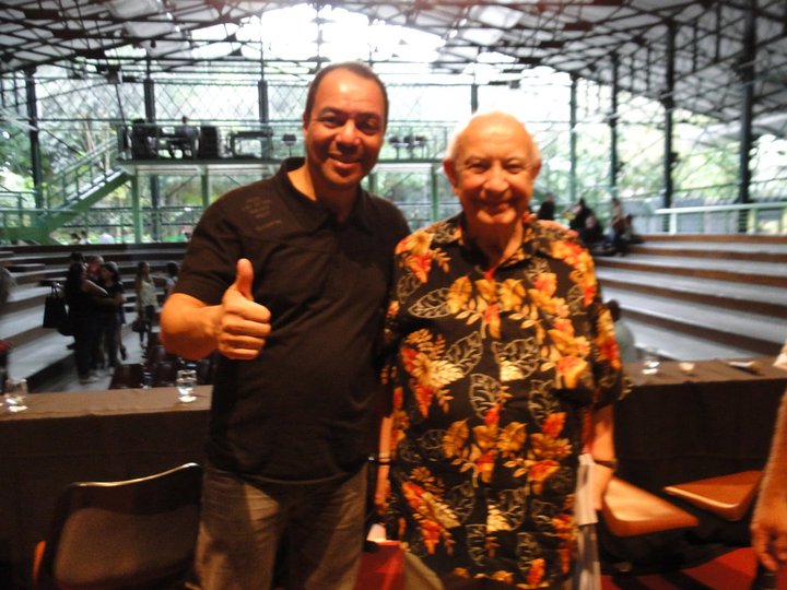 Dois participantes posam juntos junto às arquibancadas do espaço do XII Fórum Nacional de Dança.
