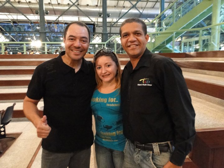 Três participantes posam juntos diante das arquibancadas no espaço do XII Fórum Nacional de Dança.