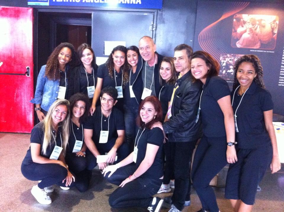 Participantes e integrantes da equipe de apoio posam juntos diante da entrada do Teatro Angel Vianna.
