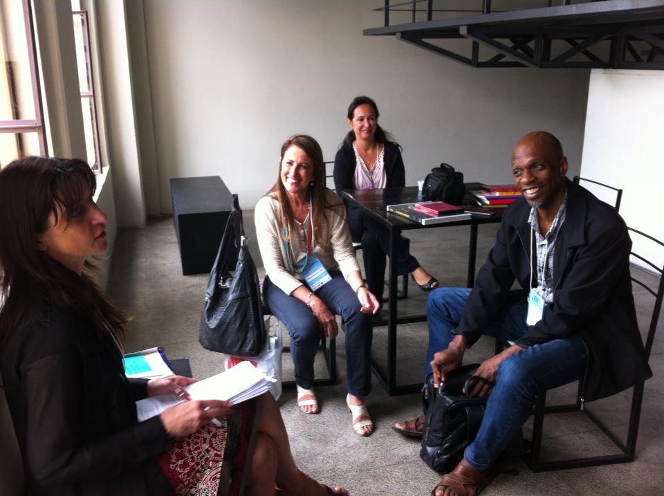 Quatro participantes conversam sentados em uma sala durante o XIII Fórum Nacional de Dança.