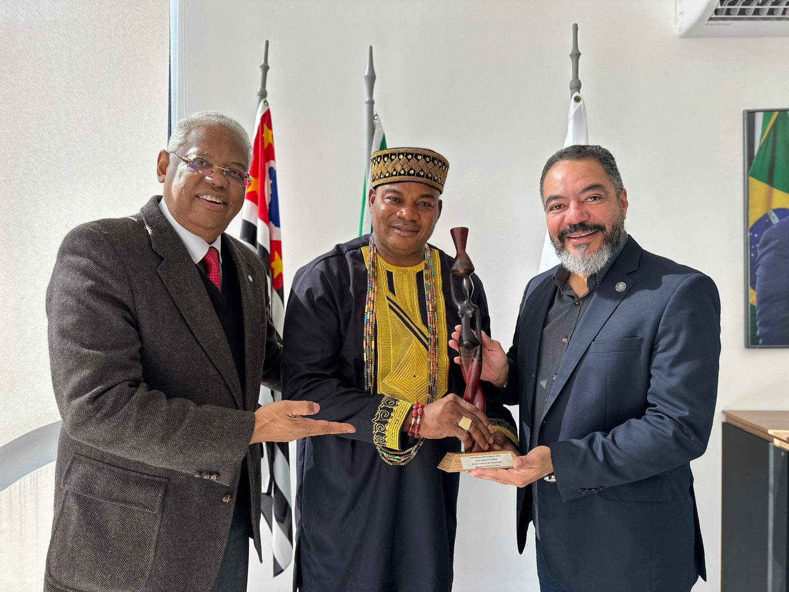 João Carlos Corrêa recebe o troféu do XIX Prêmio África Brasil das mãos de Oba Adekunle Aderonmu, presidente do Centro Cultural Africano no Brasil, acompanhado por outro participante da cerimônia